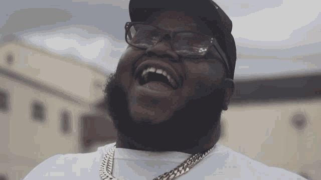 a man wearing sunglasses and a hat is laughing with his mouth open