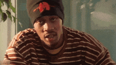 a man wearing a striped shirt and a beanie with the word wu tang on it