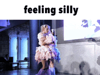 a woman in a pink dress is standing on a stage with the words feeling silly written above her
