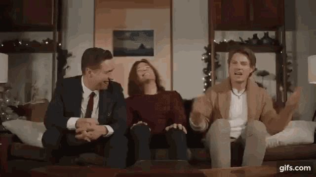 a group of people are sitting on a couch laughing and having fun .