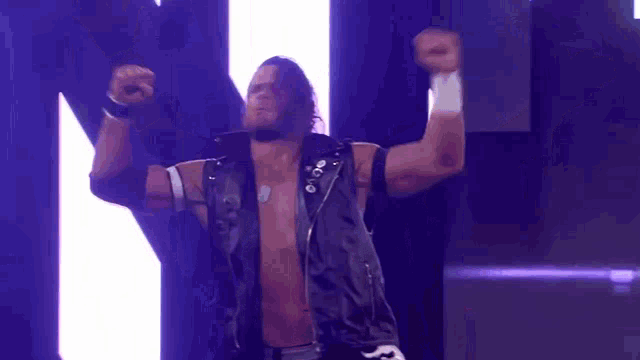 a wrestling wrestler is standing in a dark room with his arms outstretched .