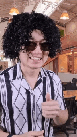 a man wearing a wig and sunglasses is smiling and giving a thumbs up