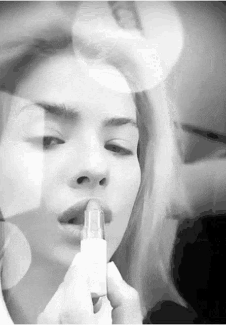 a woman is applying lipstick to her lips in a black and white photo