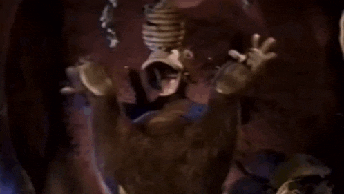 a cartoon character is sitting in a cave with his arms outstretched and screaming .