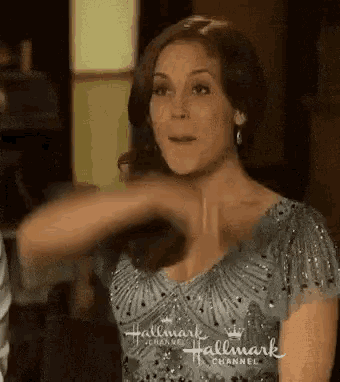 a woman in a blue dress is making a funny face while holding her hair .