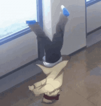 a person is doing a handstand in front of a window in a hallway .