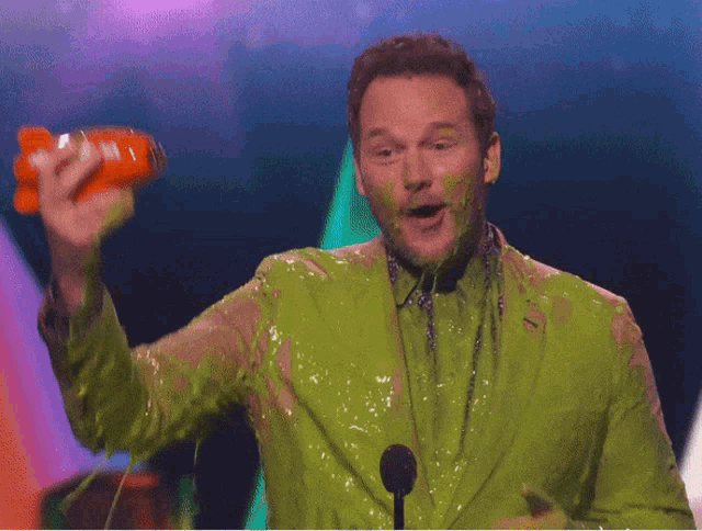 a man covered in green slime holds a nickelodeon toy