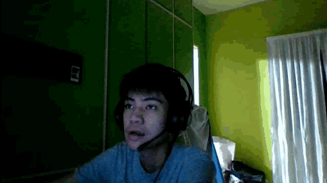 a young man wearing headphones and a microphone looks at the camera