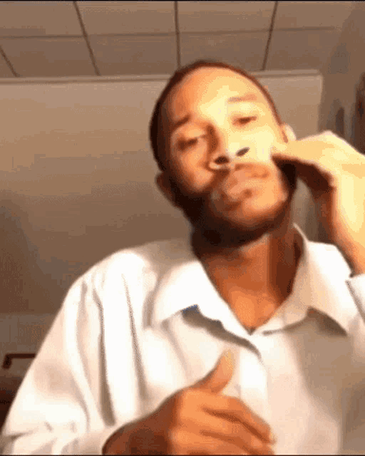 a man with a beard is wearing a white shirt and giving a thumbs up sign