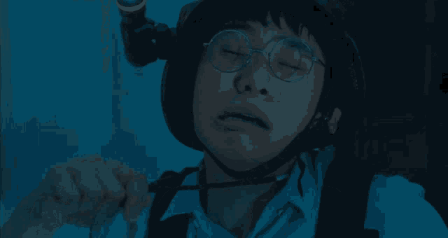 a man wearing a helmet and glasses talks to a woman in a dark room