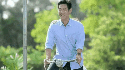 a man in a blue shirt is riding a bike with a woman on his back .