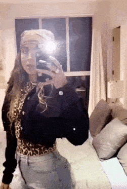 a woman is taking a selfie in front of a mirror in a bedroom .