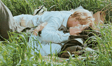 two men are laying in the grass kissing