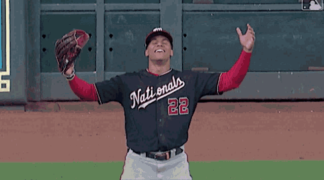 a baseball player wearing a nationals uniform holds up his glove