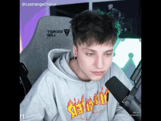 a man wearing a hoodie that says thrasher is talking into a microphone