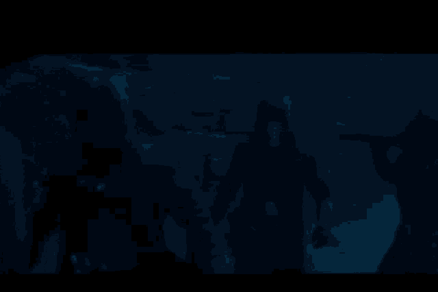 a man in a black shirt is holding a light saber in a dark cave .