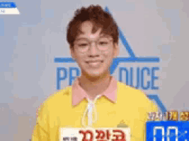 a young man wearing glasses and a yellow shirt with the word produce on it