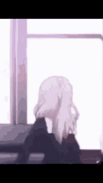 a woman with white hair is looking out a window .