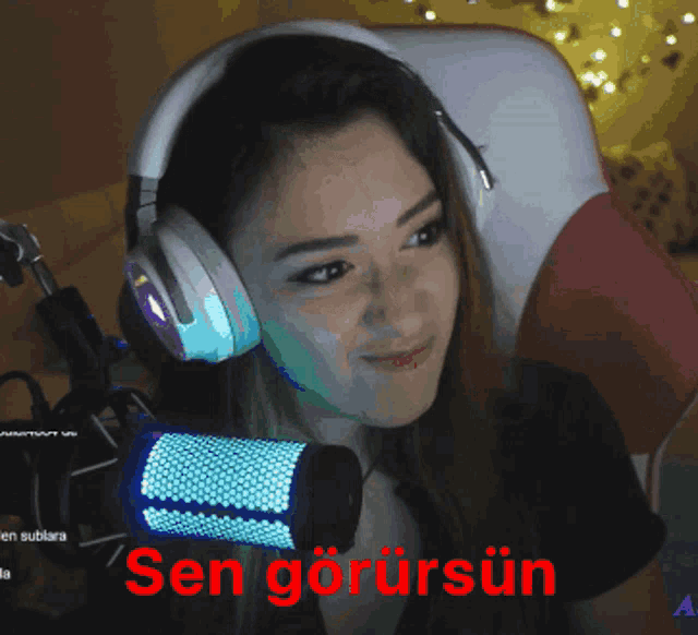 a woman wearing headphones stands in front of a microphone with the words sen gorursun written on the bottom