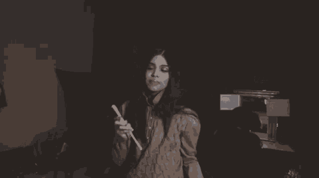 a woman in a sweater is holding a pencil in her hand