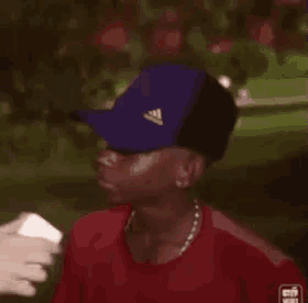 a man wearing a blue hat and a red shirt is being interviewed by a person .