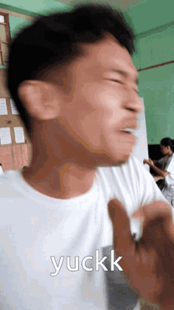 a man in a white shirt is making a funny face with the word yuckk written above him