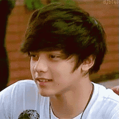 a close up of a young man 's face wearing a white shirt and a black necklace .