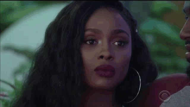 a close up of a woman wearing hoop earrings looking at a man