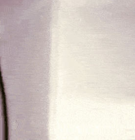 a blurry picture of a person standing in front of a white wall .