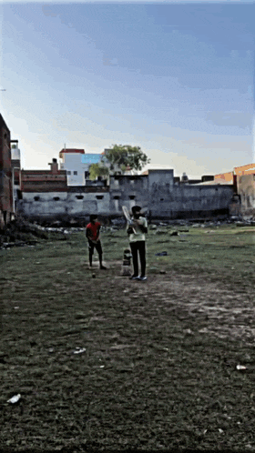 two boys are playing a game of cricket in a grassy field