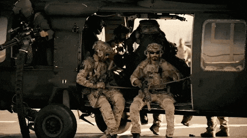 a group of soldiers are sitting in the back of a military helicopter