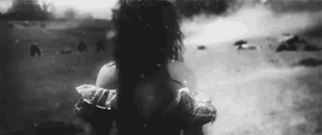 a black and white photo of a woman standing in the water .