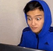 a man wearing a blue hoodie is sitting in front of a laptop computer .