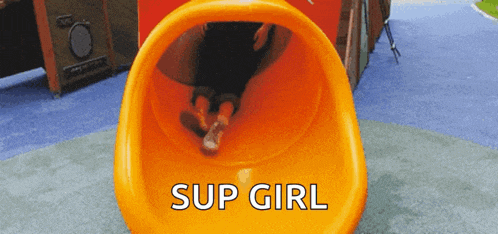 a person is going down an orange slide that says " sup girl " on it