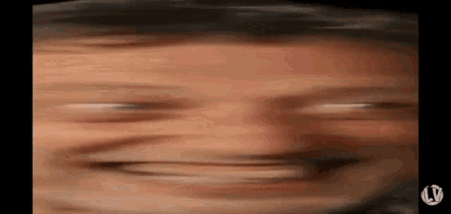 a blurry picture of a man 's face making a funny face with his eyes closed .