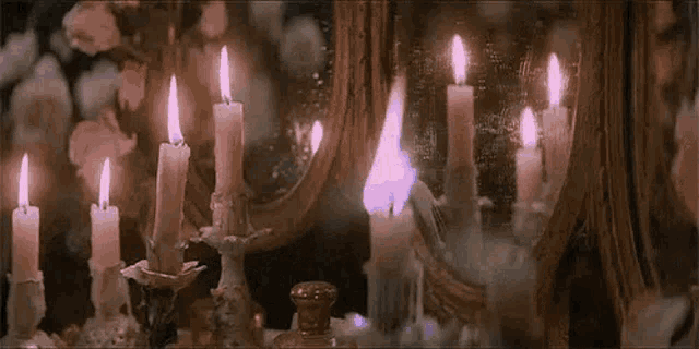 a bunch of candles are lit in front of a mirror .