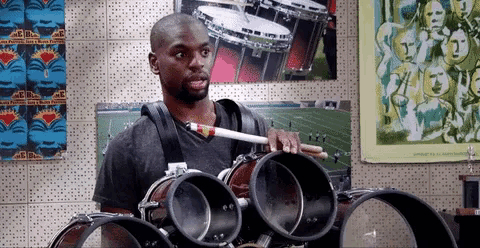 a man is playing drums in front of a wall with posters on it