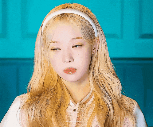 a woman with blonde hair and a white headband is making a face .