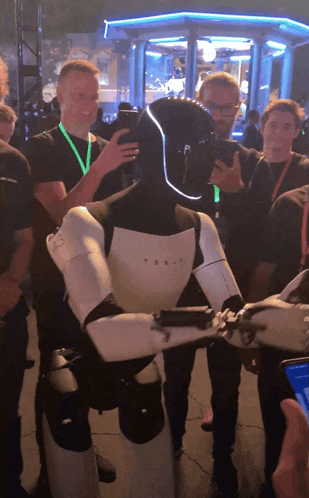 a tesla robot is surrounded by people taking pictures