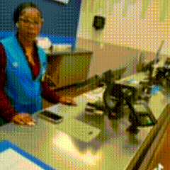 a woman in a blue vest is behind a counter