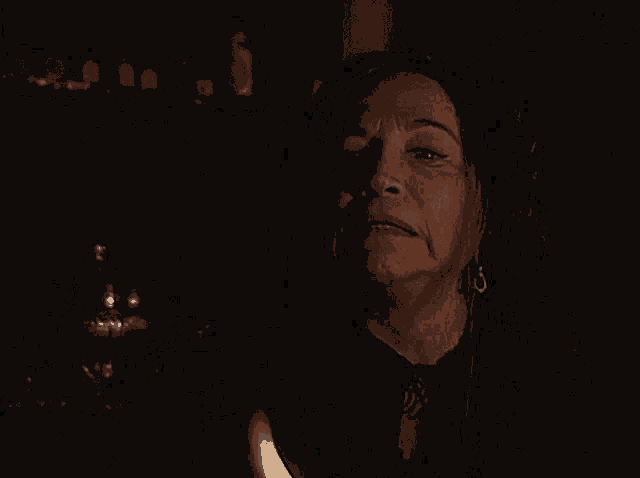 a woman in a dark room with a candle in her hand