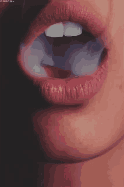 a close up of a woman 's mouth with smoke coming out of it