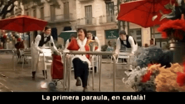 a woman sits at a table under an umbrella with the words la primera paraula en catala