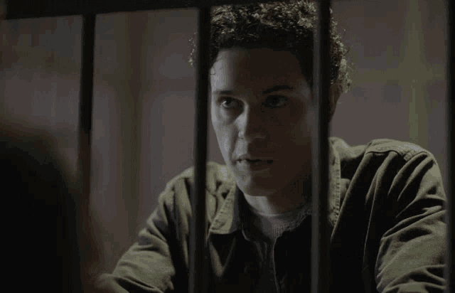 a man in a prison cell behind bars with the word prison on his shirt