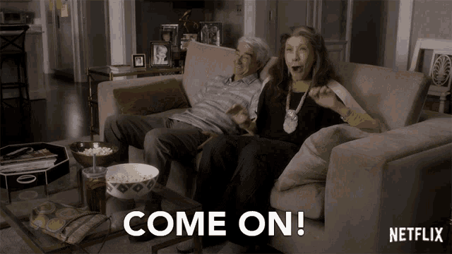 a couple sitting on a couch with the words come on written on the screen