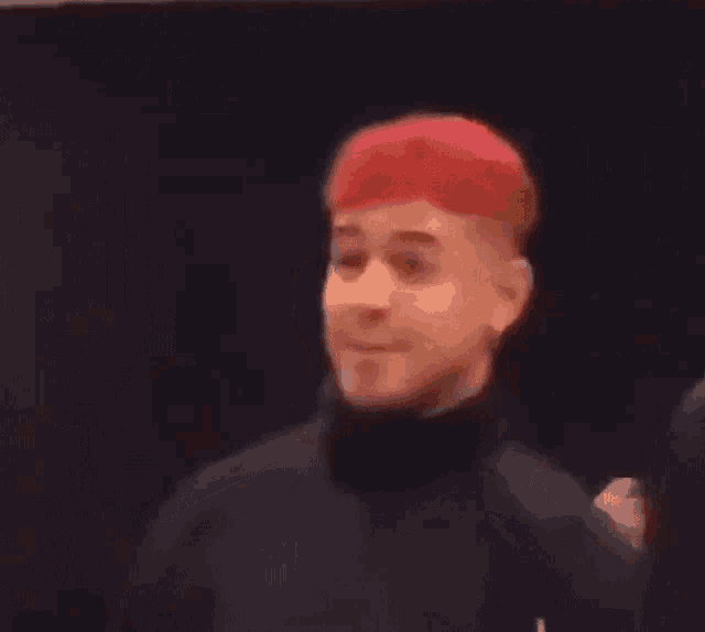 a man with red hair is wearing a black turtleneck and a black shirt .