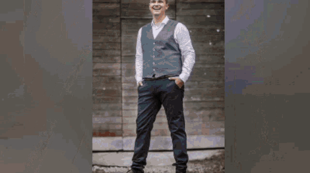 a man in a vest and tie holds a guitar