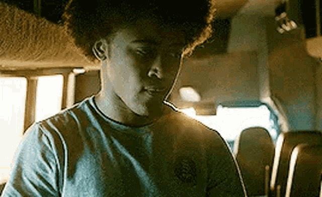 a young man is sitting in the back seat of a bus looking at his phone .