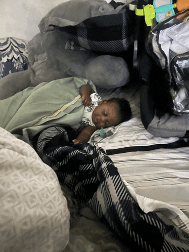a baby is sleeping on a bed with a blanket that has the letter a on it