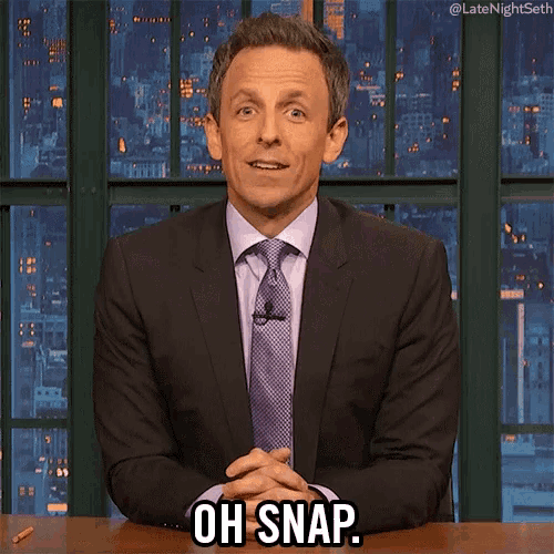 a man in a suit and tie is sitting at a desk and says oh snap